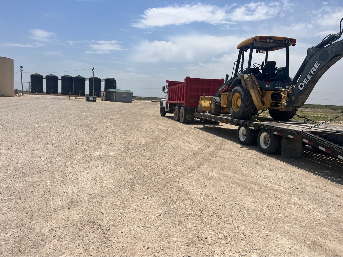 Backhoe loaded on a trailer heading to a job site