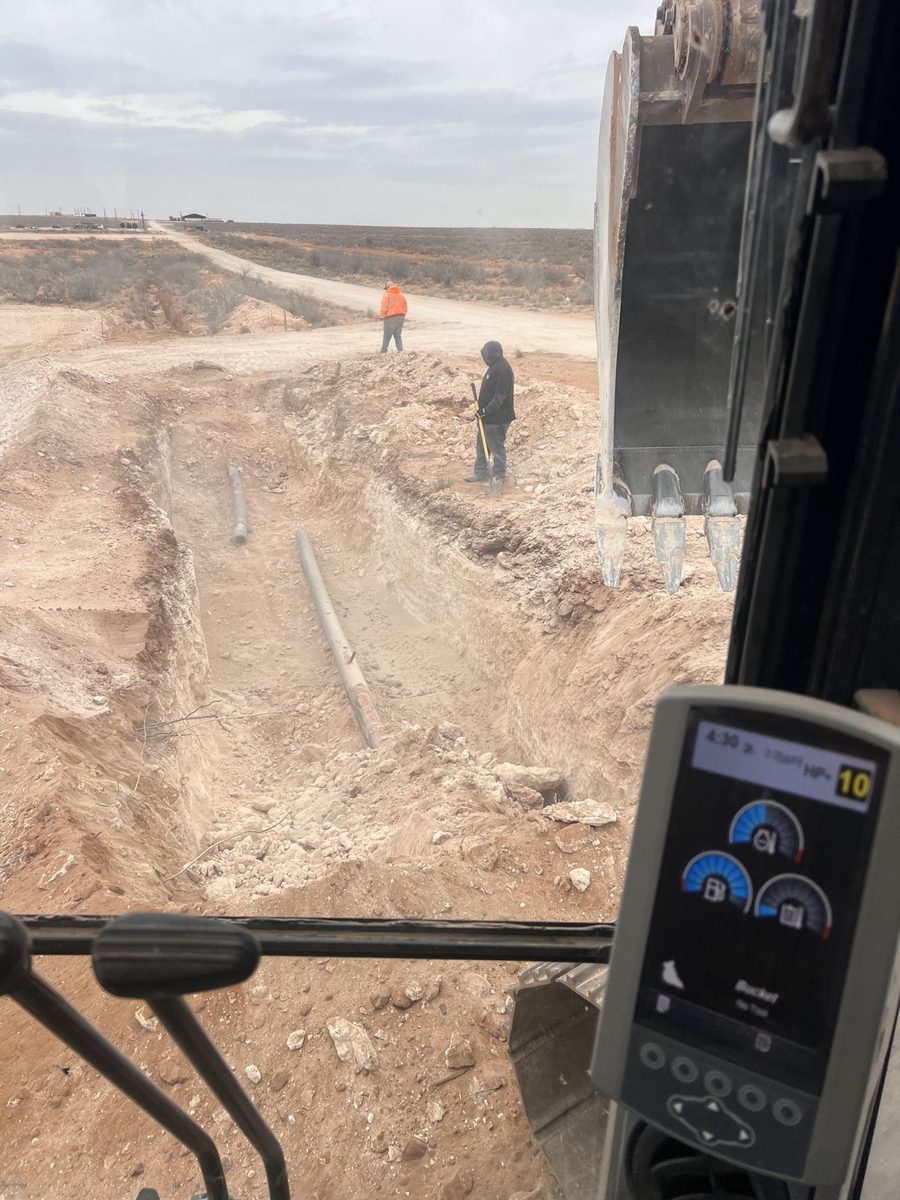 Crew performing trenching and flowline work on an oilfield location